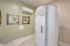 Modern wellness room featuring a sleek white cryotherapy chamber, elegant palm leaf artwork, and stylish minimalist decor.