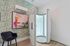 Stylish corner featuring a modern tanning booth with sleek white design, vibrant abstract artwork, and lush green leaf-patterned wallpaper.