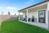 Charming backyard patio with cozy seating, lush green lawn, and modern privacy fence under a clear blue sky.