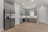 Modern kitchen with sleek gray cabinetry, stainless steel appliances, and light wood flooring, illuminated by recessed lighting.