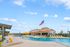 Inviting pool area with vibrant yellow loungers and a clubhouse under a clear blue sky, perfect for relaxation and leisure.