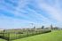 Spacious fenced dog park with agility equipment under a bright blue sky, ideal for pet-friendly living.