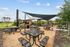 Inviting outdoor picnic area with modern shade sails, surrounded by lush greenery and spacious seating.