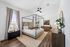 Elegant bedroom with a chic four-poster bed, stylish decor, and abundant natural light, offering a serene and inviting atmosphere.
