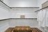 Elegant walk-in closet with ample shelving, chic robe hangers, and a stylish patterned bench, perfect for modern living.
