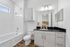 Elegant bathroom with sleek modern design, featuring a white bathtub, countertop with glossy black surface, and stylish vanity lighting.
