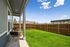 Charming patio space with comfortable chairs overlooking a lush green backyard and wooden fence under a sunny blue sky.