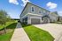 Modern townhouse exterior with a charming two-story design, featuring immaculate landscaping, a spacious driveway, and bright, inviting fa&ccedil;ades against a clear blue sky.
