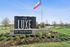 Inviting entrance to The Luxe of Denton, featuring elegant signage surrounded by lush green landscaping and vibrant flowers.