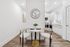 Chic dining nook with a round marble table and elegant chairs, adjacent to a modern, bright kitchen with sleek cabinetry and hardwood flooring.