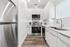 Modern kitchen with sleek white cabinetry, stainless steel appliances, and elegant wood flooring, enhanced by ample natural light.