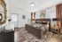 Elegant bedroom with modern decor featuring a plush bed, vibrant pillows, zebra-print rug, and abundant natural light from large windows.