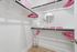 Elegant walk-in closet with modern shelving, pink accents, and ample hanging space perfect for stylish organization.