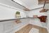 Spacious walk-in closet featuring elegant wooden hangers, soft lighting, and chic storage boxes on polished wood flooring.
