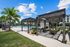 Luxurious outdoor patio featuring elegant pergolas, vibrant green seating, and a sparkling pool area surrounded by lush greenery and palm trees.