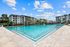 Luxurious apartment complex featuring a stunning resort-style pool with crystal-clear water, surrounded by elegant multi-story buildings and lush landscaping.