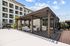 Modern outdoor seating area with elegant pergola and inviting fireplace, adjacent to a stylish apartment building.
