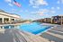 Luxurious outdoor pool area with modern lounge chairs and elegant pergolas under a clear blue sky.