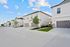 Contemporary townhouse community featuring stylish two-story homes with private driveways and lush landscaping beneath a vibrant blue sky.