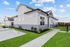 Modern duplex with sleek gray exterior, large windows, and lush landscaping under a bright blue sky.