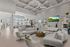 Luxurious modern living room with high ceilings, elegant white sofas, stylish decor, and a chic open-concept kitchen with pendant lighting.