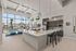 Modern kitchen and communal area featuring sleek countertops, pendant lighting, and stylish cabinetry, with large windows offering abundant natural light and a picturesque view.