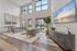 Elegant room with high ceilings, large windows, modern decor, and natural light showcasing a serene garden view.