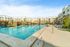 Luxurious apartment complex with a stunning resort-style pool, shaded cabanas, and ample sun loungers on a sunny day.