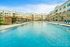 Luxurious apartment complex showcasing a stunning outdoor pool with sun loungers and modern architecture, offering a resort-style living experience.