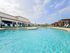 Luxurious pool area with pristine turquoise water, surrounded by stylish loungers and elegant pergolas under a bright blue sky.