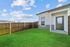 Charming backyard with lush green lawn and a modern home exterior, enclosed by a stylish wooden fence under a bright blue sky.