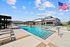 Luxurious outdoor pool area with comfortable loungers, modern architecture, and a stunning American flag waving under a clear blue sky.