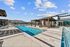 Luxurious outdoor pool area with stylish seating, surrounded by modern architecture and clear blue skies.