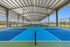 Eight covered and lighted Pickleball courts with vibrant blue surfaces and ample natural light, perfect for year-round play.