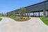 Eight covered and lighted Pickleball courts, lush landscaping, and winding pathways under a clear blue sky.