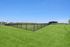 Huge enclosed dog park, perfect for playing with your dog under a clear blue sky.