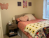 Inviting bedroom with plush bedding, decorative pillows, and a bedside table with books in a sunny atmosphere.