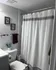 Charming bathroom with elegant decor featuring a white shower curtain, stylish wall art, and a fresh floral touch.