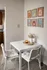 Cozy dining nook with a modern white table, two cushioned chairs, candlelit ambiance, and artistic wall decor, perfect for intimate meals.