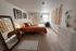 Cozy and inviting bedroom with stylish decor, featuring a comfortable bed, chic accent mirror, and a serene workspace by the window.
