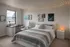 Inviting bedroom with modern decor featuring cozy queen-sized bed, elegant desk workspace, and ambient ceiling string lights.