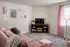 Charming living room with a plush pink sofa, colorful patterned rug, and stylish wall art, offering cozy elegance and modern flair.