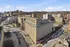 Expansive cityscape view featuring a historic building with elegant architecture, surrounded by urban development and rolling hills.