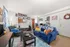 Cozy and inviting living room featuring a vibrant blue sofa with colorful cushions, accented by a modern black coffee table and natural light streaming through patterned curtains.