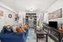 Welcoming living room with a vibrant blue couch, colorful cushions, and a stylish shelving unit filled with books and decor, creating a cozy and lively atmosphere.