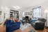 Inviting living room with plush seating, vibrant decor, abundant natural light, and stylish shelving.