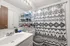 Chic bathroom showcasing a modern sink, stylish geometric shower curtain, and sleek shelving for organized storage.