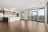 Bright, open-concept apartment with modern kitchen, sleek countertops, stainless steel appliances, and expansive windows offering stunning city views.