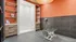 Spacious and modern grooming room with sleek cabinetry, vibrant orange accents, and advanced grooming equipment.