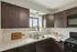 Charming kitchen with dark wood cabinets, sleek countertops, and a stunning view from a bright window.